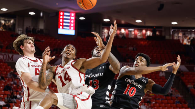 Mar 5, 2024; Norman, Oklahoma, USA; Oklahoma Sooners forward Jalon Moore (14) reaches for rebound in front of Cincinnati Bearcats forward Jamille Reynolds (13) and guard Josh Reed (10) during the first half at Lloyd Noble Center. Mandatory Credit: Alonzo Adams-USA TODAY Sports